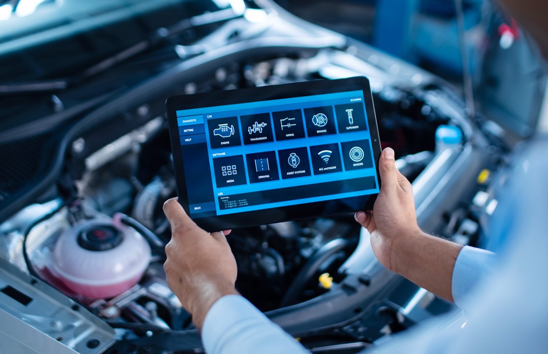 a mechanic tightening a bolt in a car hood