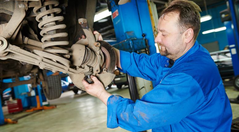 a mechanic tightening a bolt in a car hood