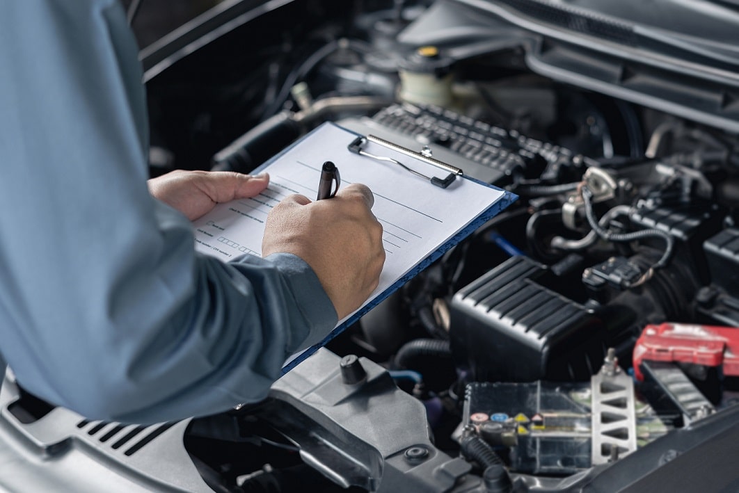 a mechanic tightening a bolt in a car hood