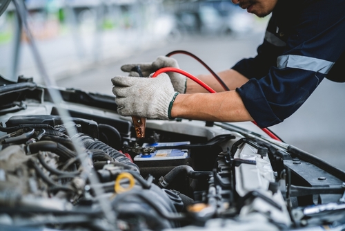 a mechanic tightening a bolt in a car hood